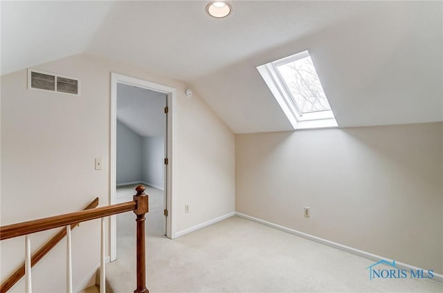 additional living space with vaulted ceiling with skylight and light carpet