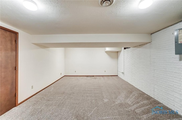 basement with brick wall, carpet floors, and a textured ceiling