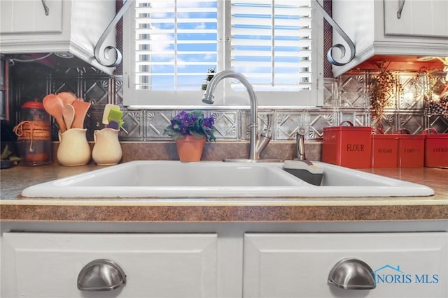 room details with sink, a fireplace, and white cabinets