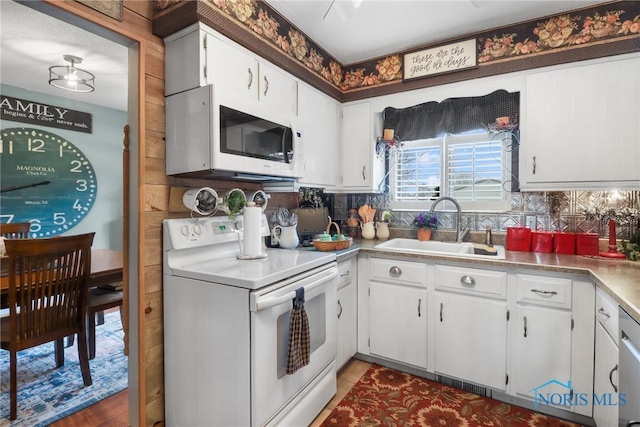 kitchen featuring sink, white appliances, white cabinetry, tile patterned flooring, and tasteful backsplash