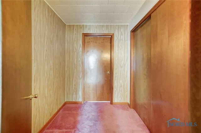 hallway with light colored carpet and wooden walls