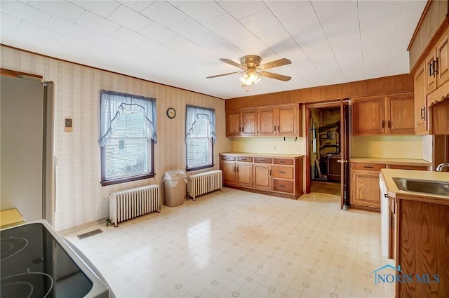 kitchen featuring ceiling fan, radiator, sink, and stainless steel refrigerator