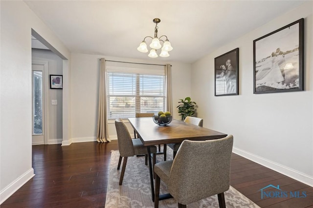 dining room with dark hardwood / wood-style floors and a notable chandelier