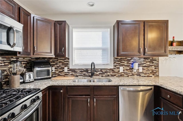 kitchen featuring stainless steel appliances, sink, backsplash, and dark brown cabinetry