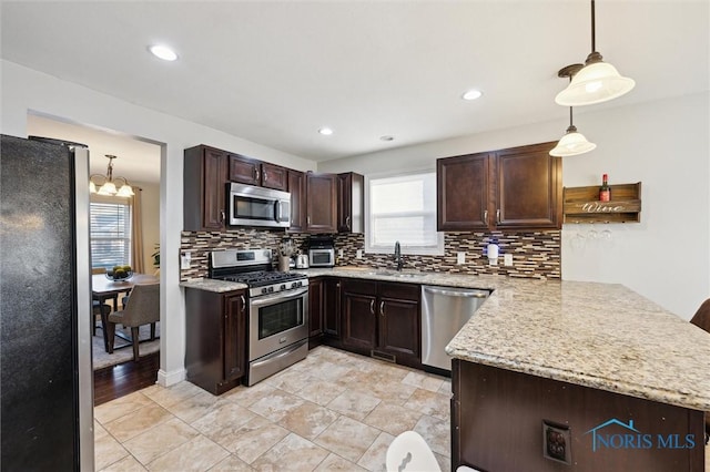 kitchen with pendant lighting, tasteful backsplash, kitchen peninsula, and appliances with stainless steel finishes