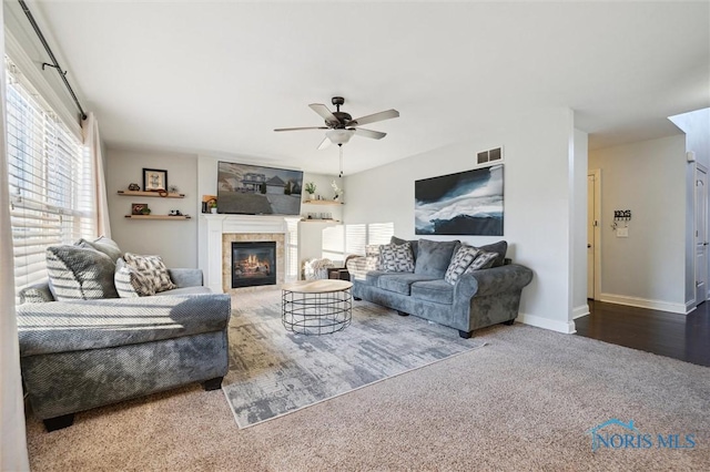 living room with ceiling fan, a tiled fireplace, and carpet