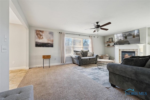 carpeted living room with a tiled fireplace and ceiling fan