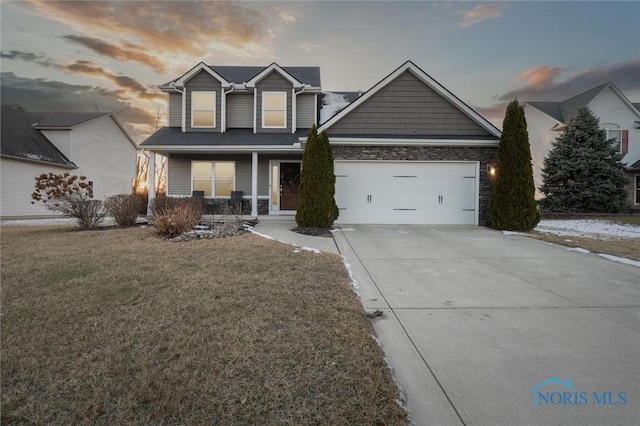 view of front of home with a garage, a lawn, and covered porch