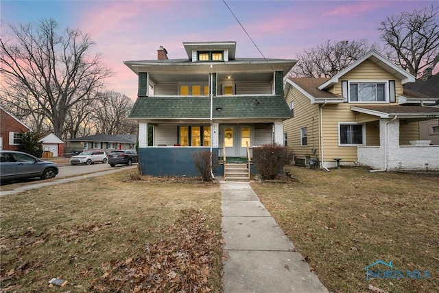 view of front of house with a lawn, french doors, a balcony, and covered porch