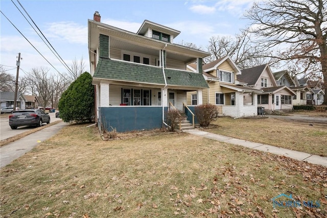 view of front of house featuring a balcony and a front lawn