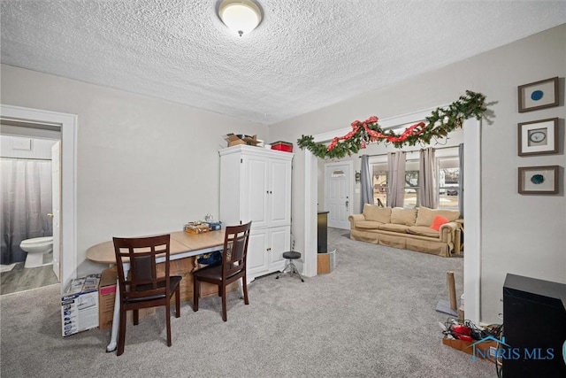 dining space featuring light carpet and a textured ceiling