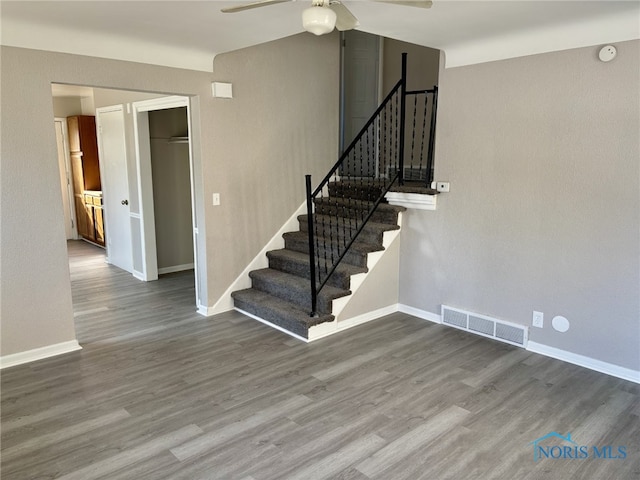 staircase with wood-type flooring and ceiling fan