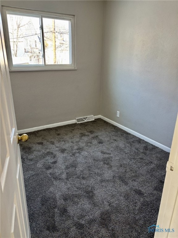 unfurnished room featuring dark carpet