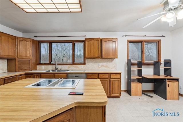 kitchen with butcher block countertops, sink, ceiling fan, electric stovetop, and decorative backsplash