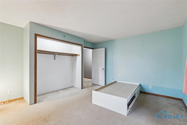 unfurnished bedroom featuring light carpet, a closet, and a textured ceiling