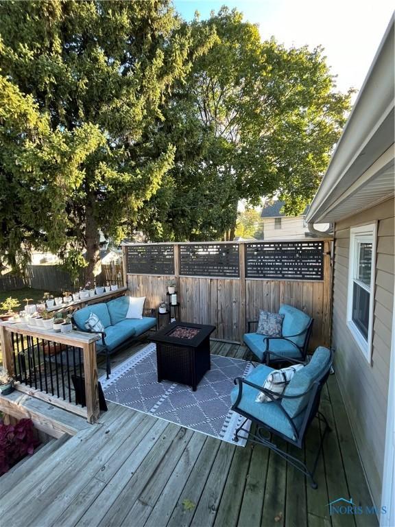 wooden deck featuring an outdoor living space with a fire pit