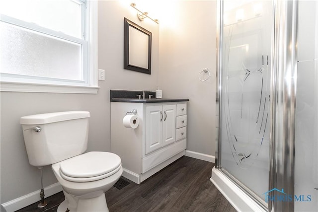 bathroom featuring vanity, wood-type flooring, a shower with door, and toilet