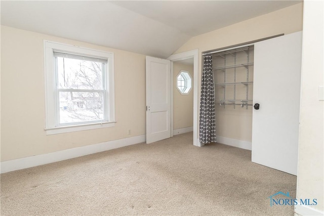 unfurnished bedroom with lofted ceiling, carpet flooring, and a closet