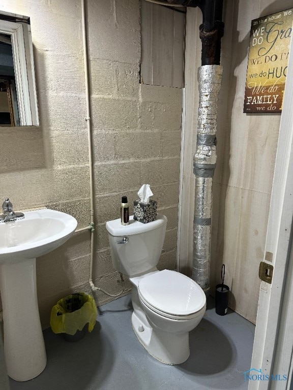 bathroom featuring sink, concrete flooring, and toilet