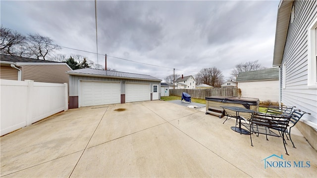 view of patio with a garage, a hot tub, and an outdoor structure