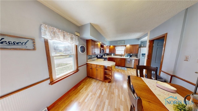 kitchen with stainless steel appliances, a textured ceiling, and light wood-type flooring