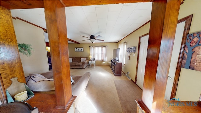 carpeted living room featuring crown molding, ceiling fan, and ornate columns