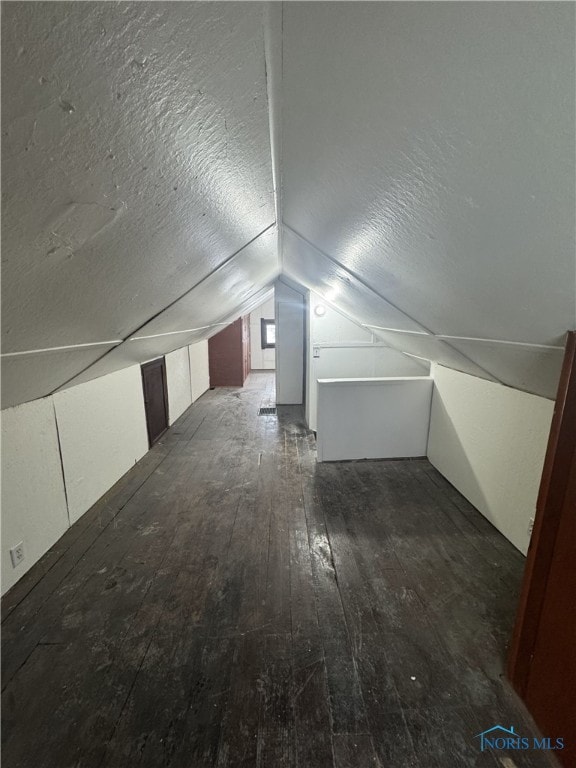 bonus room featuring vaulted ceiling, dark hardwood / wood-style floors, and a textured ceiling