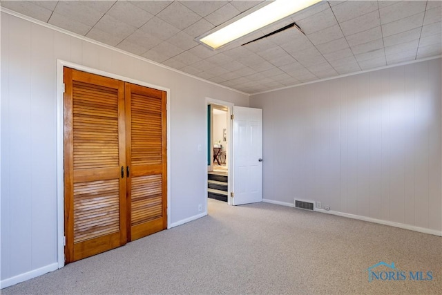 unfurnished bedroom with crown molding, light colored carpet, and a closet