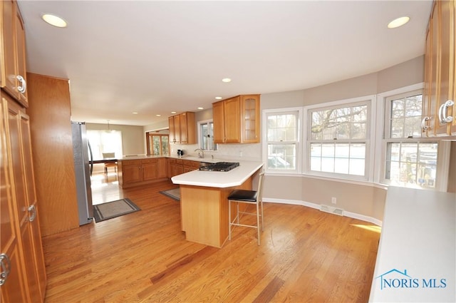 kitchen featuring light hardwood / wood-style flooring, stainless steel fridge, a kitchen bar, and kitchen peninsula