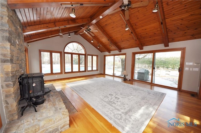 unfurnished living room featuring wood ceiling, beamed ceiling, light hardwood / wood-style flooring, and a wood stove