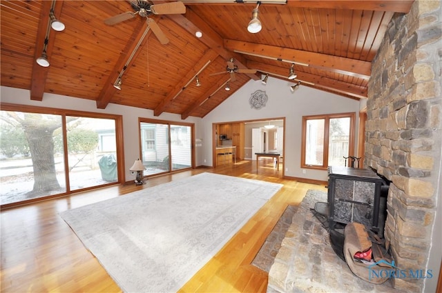 living room with wooden ceiling, a healthy amount of sunlight, light hardwood / wood-style flooring, and a wood stove