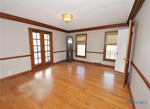 unfurnished room featuring crown molding, light hardwood / wood-style floors, and french doors