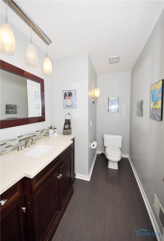 bathroom featuring vanity, toilet, hardwood / wood-style floors, and backsplash