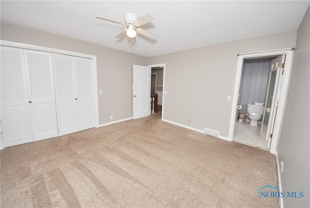 unfurnished bedroom with ensuite bath, light colored carpet, a closet, and ceiling fan