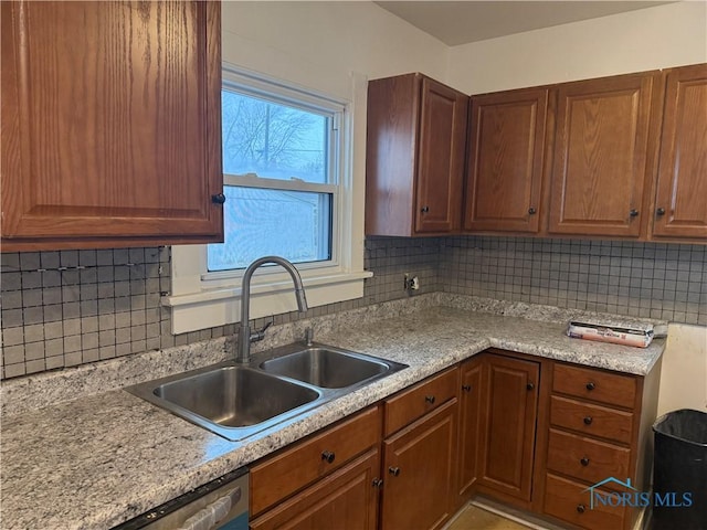 kitchen featuring dishwasher, brown cabinets, a sink, and decorative backsplash