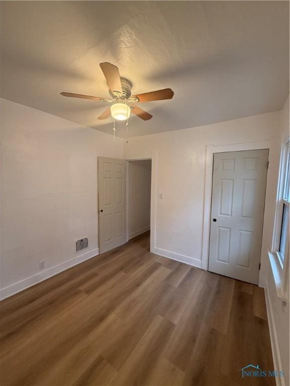 unfurnished bedroom with baseboards, visible vents, ceiling fan, and wood finished floors