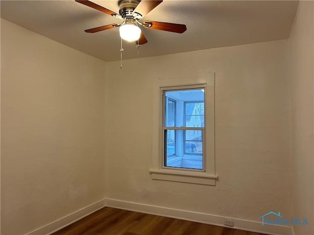 empty room featuring dark wood-style flooring, ceiling fan, and baseboards