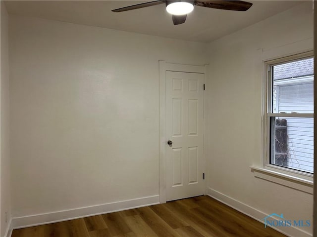 unfurnished room with ceiling fan, baseboards, and dark wood finished floors