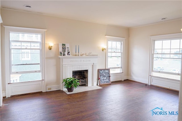 unfurnished living room with crown molding, dark hardwood / wood-style flooring, and a tiled fireplace