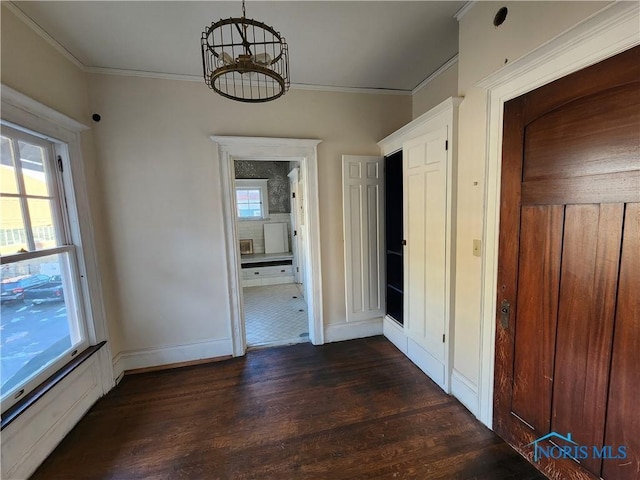 unfurnished dining area featuring ornamental molding, dark hardwood / wood-style flooring, and a chandelier