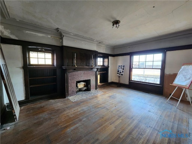 unfurnished living room with ornamental molding, a brick fireplace, and hardwood / wood-style floors