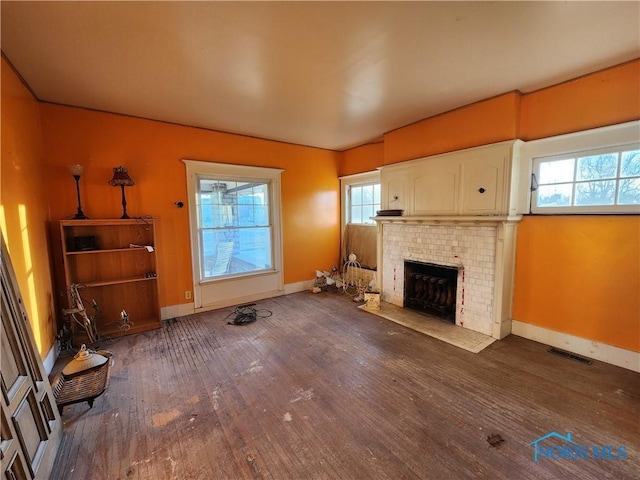 unfurnished living room with a brick fireplace and dark wood-type flooring