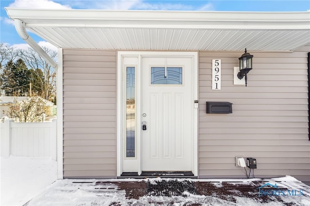 snow covered property entrance with fence