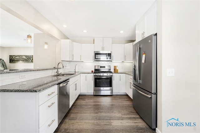 kitchen with dark stone counters, a peninsula, appliances with stainless steel finishes, and white cabinets