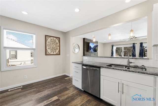 kitchen featuring dark stone counters, white cabinets, dishwasher, and a sink