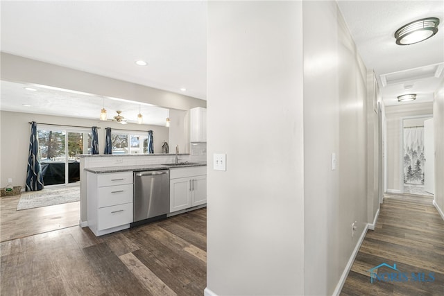 kitchen featuring a peninsula, dark wood-type flooring, white cabinets, and stainless steel dishwasher