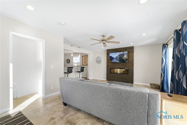 living area featuring a large fireplace, plenty of natural light, light wood-style flooring, and recessed lighting