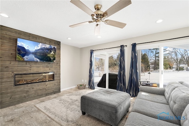 living area featuring a large fireplace, baseboards, light wood finished floors, and recessed lighting