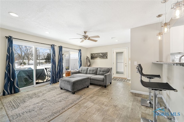 living room featuring recessed lighting, a ceiling fan, a textured ceiling, wood finished floors, and baseboards