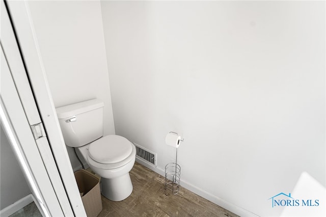 bathroom featuring toilet, baseboards, visible vents, and wood finished floors